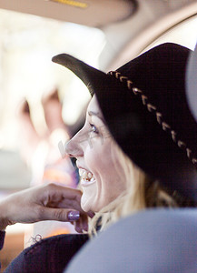 肩上是戴着帽子的年轻女子坐在车里微笑的景象