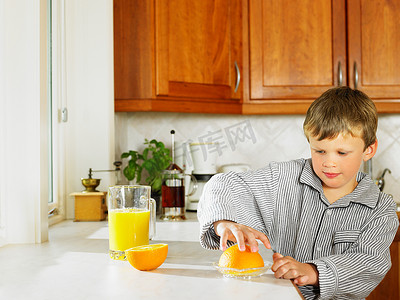 卡台面摄影照片_小男孩在厨房里做橙汁