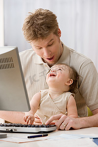 父母与孩子沟通摄影照片_使用电脑的父亲和女儿
