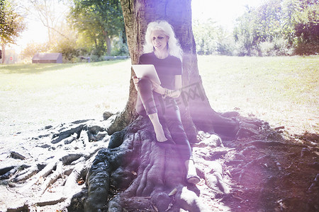 高级背景光斑摄影照片_白发女子在城市公园休息阅读数字平板电脑