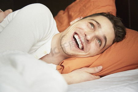 年轻人躺在床上大笑的特写