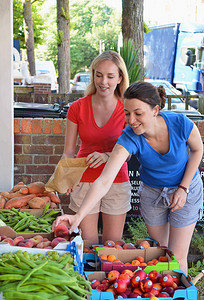 两名年轻女子在市场摊位上挑选水果