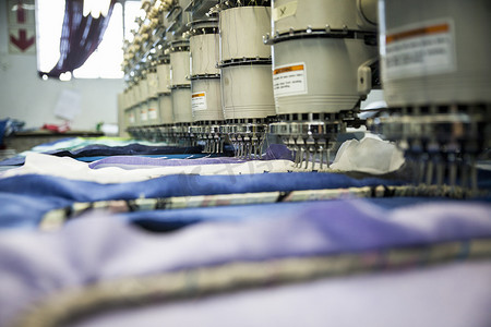 一排排程控绣花机在服装厂快速缝制蓝色布料