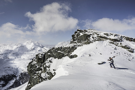 中年女性运动摄影照片_中年男子滑雪者带着滑雪板走上山顶瑞士科瓦奇