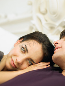 家具门头摄影照片_年轻夫妇躺在床上女人的头靠在男人的肩膀上