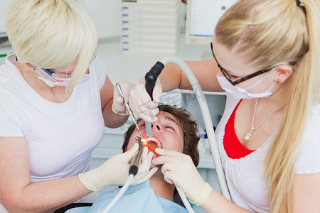闭着眼睛摄影照片_牙医在治疗病人的牙齿