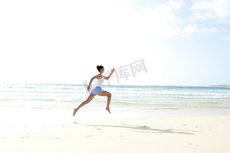 中年女性运动摄影照片_非洲佛得角一名中年妇女赤脚在海滩上奔跑