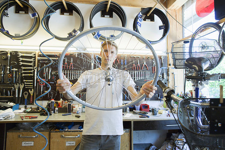 力学摄影照片_维修店的中年男子在看自行车轮子