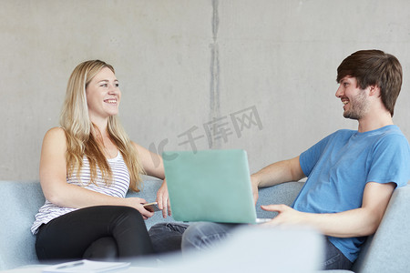 高等教育学院的年轻男女学生坐在学习空间的沙发上使用笔记本电脑