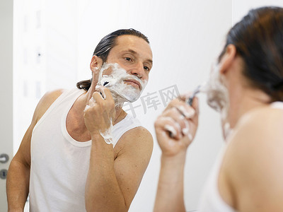 卫生间浴室镜摄影照片_一名男子在浴室里刮脸