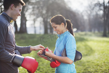 年轻男女摄影照片_年轻男女戴上拳击手套在公园训练