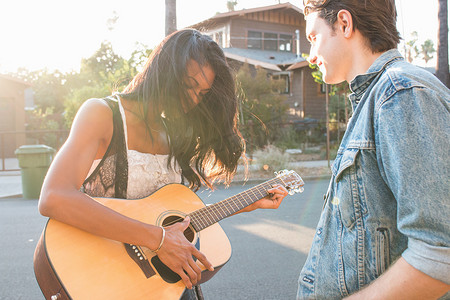 幸福邻里摄影照片_年轻夫妇在户外年轻女子弹吉他