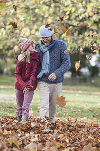 父女俩在公园里闲逛穿行在秋叶中