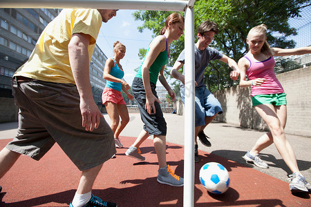 一群人踢足球摄影照片_朋友们在城市街道上踢足球