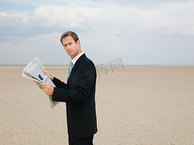 阅读之门摄影照片_在沙漠里看报的商人