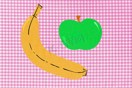 粉色格子棉布背景上的香蕉和苹果