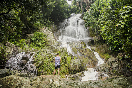 泰国苏梅岛一名年轻男子站在岩石上看着那蒙瀑布