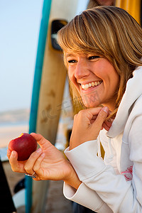 苹果游戏摄影照片_一名女子在冲浪板附近吃苹果