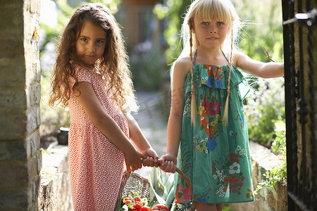 儿童牛肉摄影照片_两个女孩在花园里提着一篮子新鲜西红柿