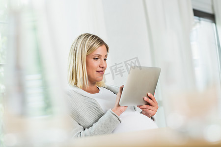 在数字平板电脑上使用触摸屏的足月怀孕年轻女性