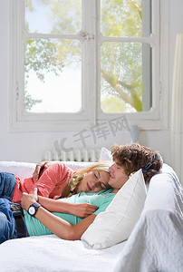 闭着眼睛摄影照片_年轻夫妇睡在家里的沙发上
