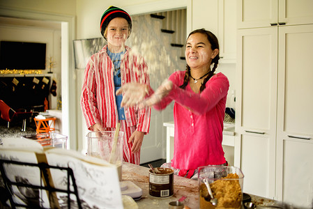 十几岁的女孩和兄弟在厨房里扔面粉