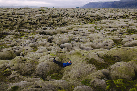 冰岛中年妇女躺在起伏的火山地貌上的侧视