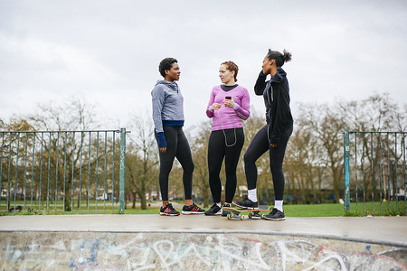 三名年轻女子滑板运动员在滑板公园聊天