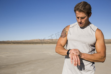 美国加利福尼亚州埃尔米拉奇男子培训在干涸的湖床上检查智能手表