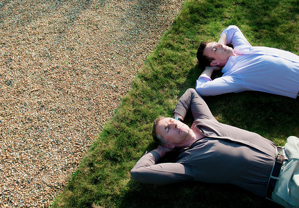 闭着眼睛摄影照片_两个商人在草地上睡着了