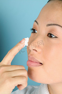 东南亚人摄影照片_女性将保湿霜涂在脸颊上