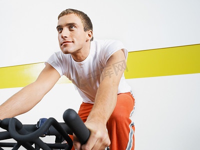 游戏手柄摄影照片_健身俱乐部里骑着健身车的男子