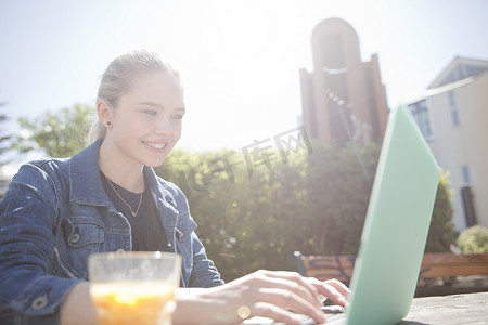 冰岛雷克雅未克十几岁的女孩坐在户外使用笔记本电脑微笑着俯视