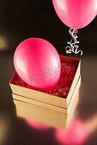 保护蜡烛摄影照片_带有粉色派对气球的纸箱