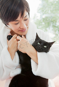 穿浴袍的女人抱着猫
