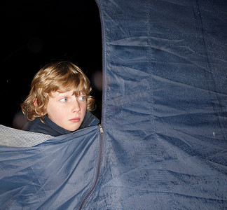 黄昏时分从帐篷里往外看的男孩