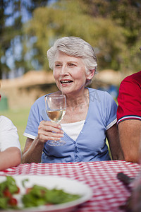 年长的妇女在野餐桌上喝酒