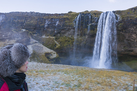 一名女子正在观看冰岛西南部的塞尔贾兰德斯福斯瀑布