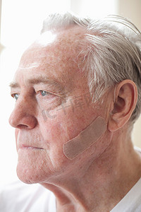 皮肤老化摄影照片_脸颊上贴着橡皮膏的老人肖像