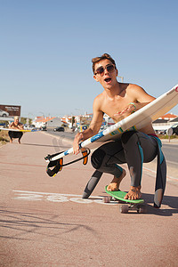一名年轻男子手持冲浪板沿着街道滑板