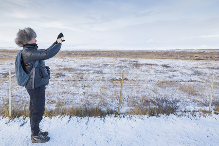 冰岛一名成年女子在积雪覆盖的田野上拍照