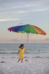 在美国佛罗里达州安娜玛丽亚岛的海滩上女孩围着五颜六色的海滩伞奔跑