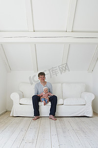 成熟的父亲和小女儿坐在沙发上的肖像