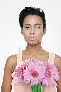 花朵摆动摄影照片_一位手持粉色花朵的年轻女子