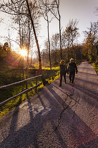 城市漫步摄影照片_秋天意大利伦巴第一对老年夫妇在阳光明媚的乡间小路上散步