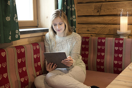 一名年轻女子在木屋里阅读数字平板电脑