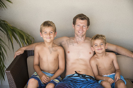 美国加利福尼亚州拉古纳海滩男人和两个儿子坐在露台沙发上的肖像