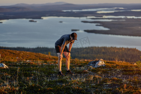 日落时分芬兰拉普兰基米奥图里一名男子在悬崖顶上跑步后休息