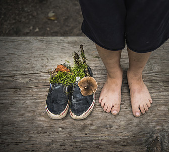 男孩赤脚站在充满自然的鞋子旁