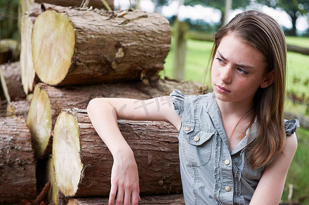 十几岁的女孩在森林里靠在原木上